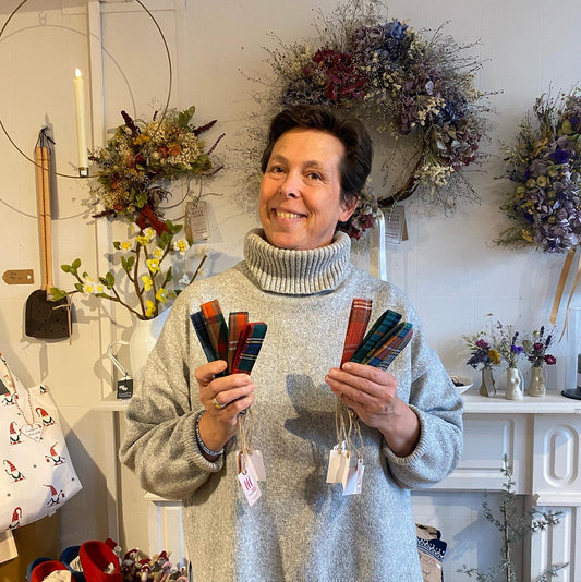 Helle of Beech & Birch in Gifford holding handmade tartan keyrings in her shop